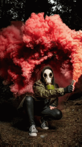 A Person Wearing A Gas Mask Is Holding A Smoke Bomb GIF