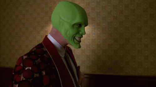 A Person Wearing A Green Mask Is Standing In Front Of Two Lamps GIF