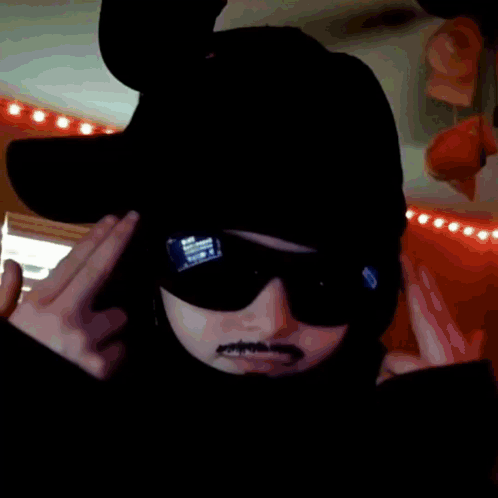 A Person Wearing A Hat And Sunglasses Is Making A Funny Face GIF