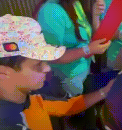 A Person Wearing A Hat With A Sun On It Is Holding A Red Object GIF