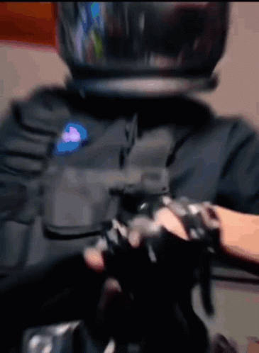 A Person Wearing A Helmet And Gloves Is Holding A Gun GIF