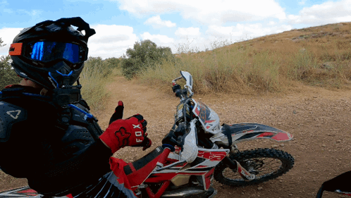 a person wearing a helmet and gloves that say fox giving a thumbs up