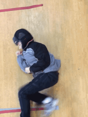 A Person Wearing A Hooded Jacket And Goggles Is Laying On A Wooden Floor GIF