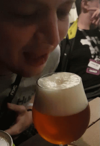 A Person Wearing A Lanyard That Says ' Snc ' On It Looks At A Glass Of Beer GIF