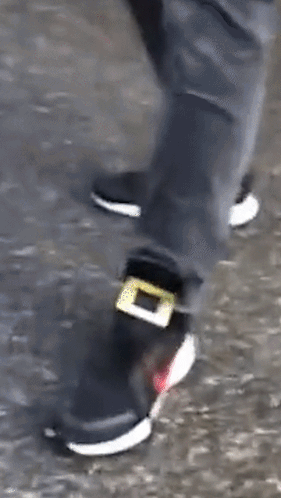A Person Wearing A Pair Of Black And White Shoes With A Yellow Buckle On The Side . GIF