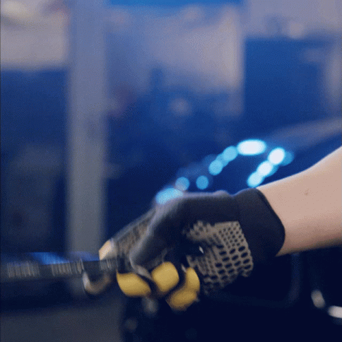 A Person Wearing A Pair Of Black And Yellow Gloves Is Holding A Yellow Object GIF