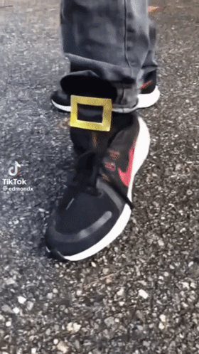 A Person Wearing A Pair Of Black Nike Shoes With A Gold Buckle GIF