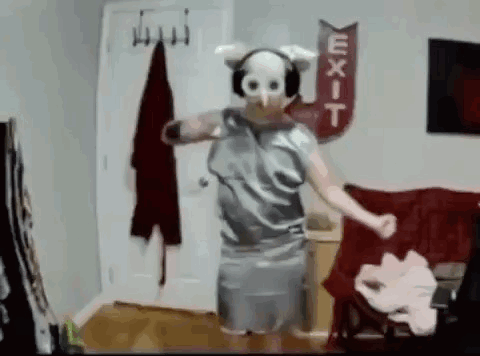 A Person Wearing A Pig Mask And Headphones Is Dancing In A Living Room . GIF