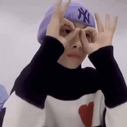 A Person Wearing A Purple Hat And A Black And White Sweater Is Making A Funny Face . GIF