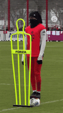 A Person Wearing A Red Jersey With The Letter F On It Stands Next To A Yellow Forza Mannequin GIF