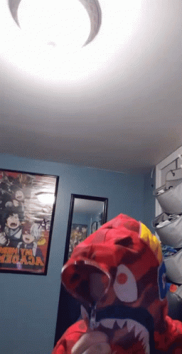 A Person Wearing A Red Shark Hoodie In A Room With A Poster That Says My Hero Academia GIF