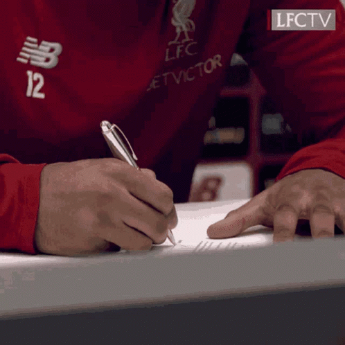 A Person Wearing A Red Shirt With The Number 12 On It Is Writing On A Piece Of Paper GIF