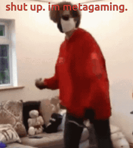 A Person Wearing A Red Sweater And A Mask Is Standing In A Living Room With The Words Shut Up . Im Metagaming . GIF