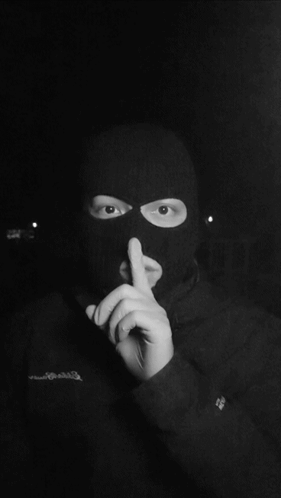 A Person Wearing A Ski Mask Has Their Finger To Their Mouth GIF