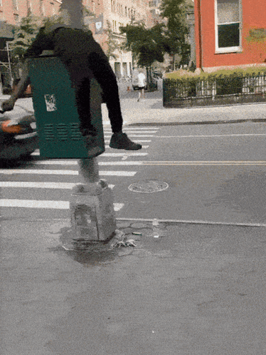 A Person Wearing A Trash Can On Their Back Is Crossing The Street GIF