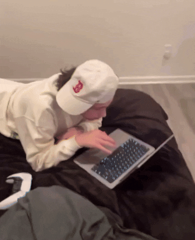 A Person Wearing A White Hat With The Letter B On It Is Using A Laptop GIF