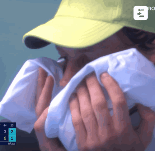 A Person Wearing A Yellow Hat Covering Their Face With A Towel GIF
