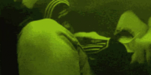 A Person Wearing An Adidas Jacket Is Standing In A Dark Room With A Green Background . GIF