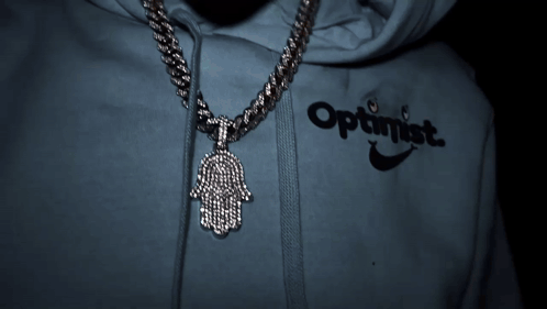 A Person Wearing An Optimistic Hoodie With A Hamsa Pendant GIF