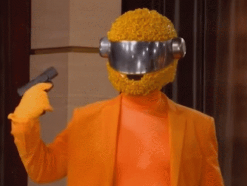 A Person Wearing An Orange Suit And A Yellow Helmet Is Holding A Gun To Their Head GIF
