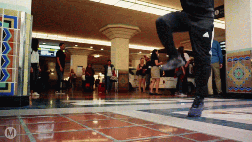 A Person Wearing Black Adidas Pants Is Dancing In A Crowded Room GIF