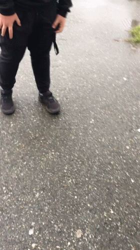 A Person Wearing Black Pants And Black Shoes Is Standing On A Concrete Surface GIF