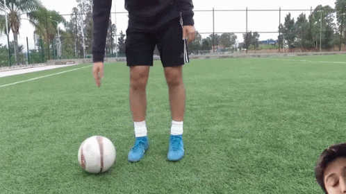 A Person Wearing Blue Adidas Shorts Kicks A Soccer Ball GIF