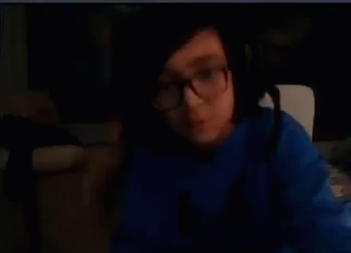 A Person Wearing Glasses And A Blue Shirt Is Making A Funny Face . GIF
