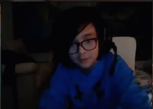 A Person Wearing Glasses And A Blue Sweater Is Sitting In Front Of A Computer Screen . GIF