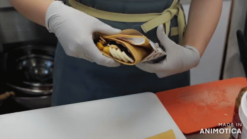 A Person Wearing Gloves Is Holding A Food Item That Says Made In Animatica GIF