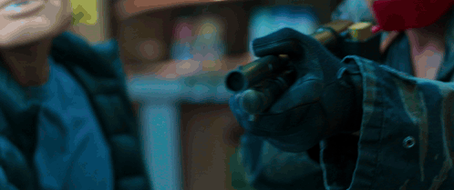A Person Wearing Gloves Is Holding A Gun In Their Hand . GIF