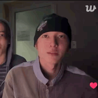 a person wearing headphones and a beanie is clapping their hands .