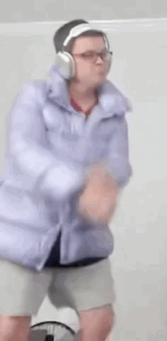 A Person Wearing Headphones And A Purple Jacket Is Dancing . GIF
