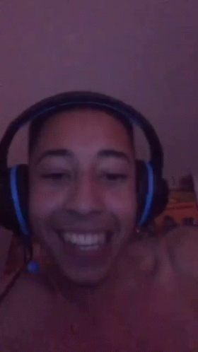 A Person Wearing Headphones Is Smiling And Making A Funny Face GIF