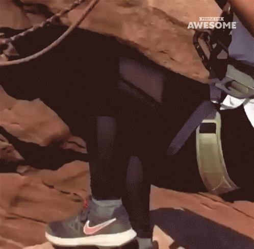 A Person Wearing Nike Shoes Climbs A Rocky Hillside GIF