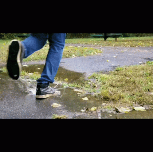 A Person Wearing Nike Shoes Runs Through A Puddle Of Water GIF