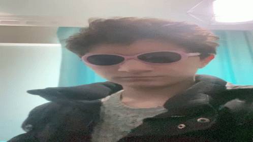 A Person Wearing Sunglasses And A Black Jacket Looks Down GIF