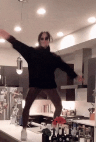 A Person Wearing Sunglasses And A Black Sweater Is Jumping In The Air GIF