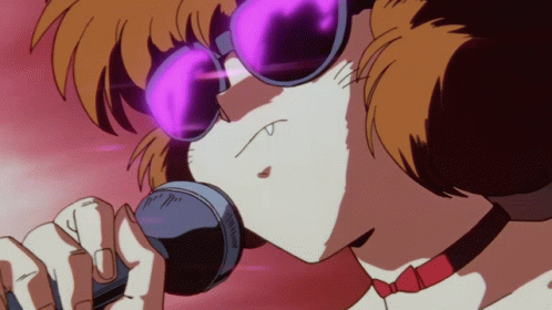 A Person Wearing Sunglasses And A Choker Singing Into A Microphone GIF