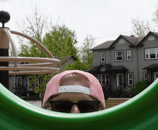 A Person Wearing Sunglasses And A Pink Hat Looks Out Of A Green Circle GIF