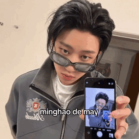 A Person Wearing Sunglasses Is Holding Up A Cell Phone With The Name Minghao De May Written On The Screen GIF