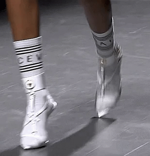A Person Wearing White Socks And White Boots Is Walking On A Tile Floor . GIF