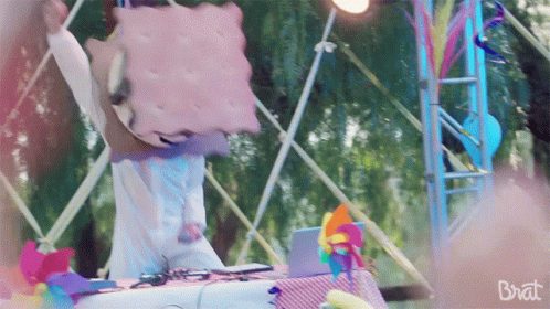 A Person With A Cookie On Their Head And The Word Brat On The Bottom Right GIF