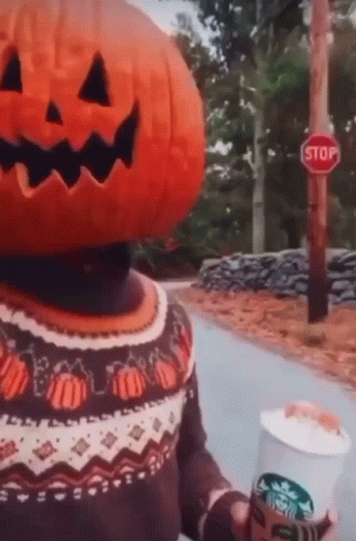 A Person With A Pumpkin On Their Head Is Holding A Starbucks Cup Of Coffee . GIF