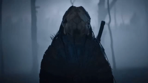 A Person With A Skull On Their Head Holding A Sword In The Fog GIF