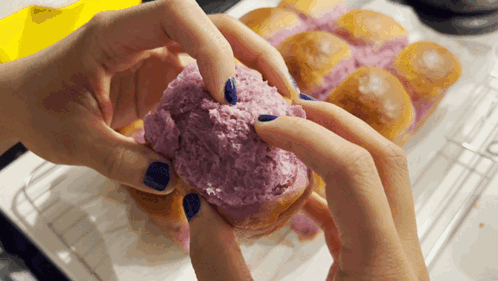 A Person With Blue Nails Is Holding A Purple Donut GIF