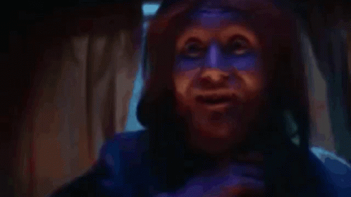 A Person With Blue Paint On Their Face Is Talking On A Cell Phone . GIF