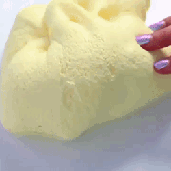 A Person With Purple Nails Is Holding A Piece Of Yellow Foam . GIF