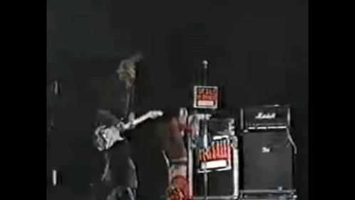 A Person With Spikes On Their Head Is Standing In A Dark Room GIF