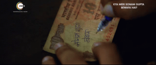 a person writing on a 10 rupee note